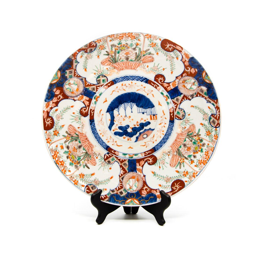 Antique Imari Hand-Painted Porcelain Platter: An antique Imari hand-painted porcelain platter. This piece features a scenic design in the center completed with a repating floral basket design border. It is unmarked. Dimensions: 14.75"H x 14.75"W 