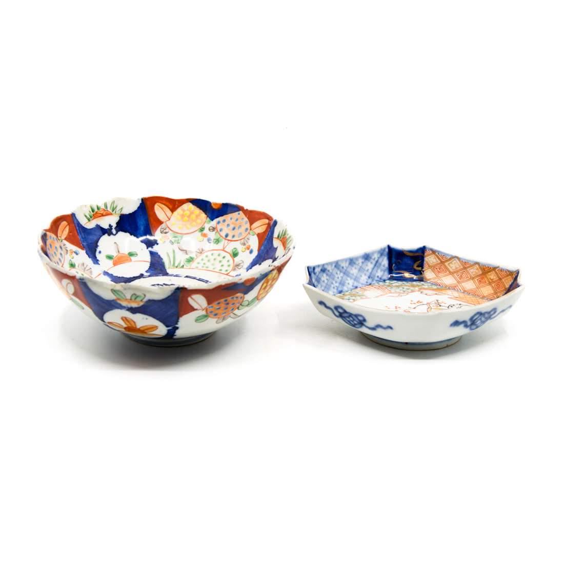 Antique Imari Hand-Painted Porcelain Bowls: A grouping of two antique Imari hand-painted porcelain bowls. The larger bowl features a paneled floral, foliate, and fruit design. The smaller bowl features a crane design in the center bordered by f
