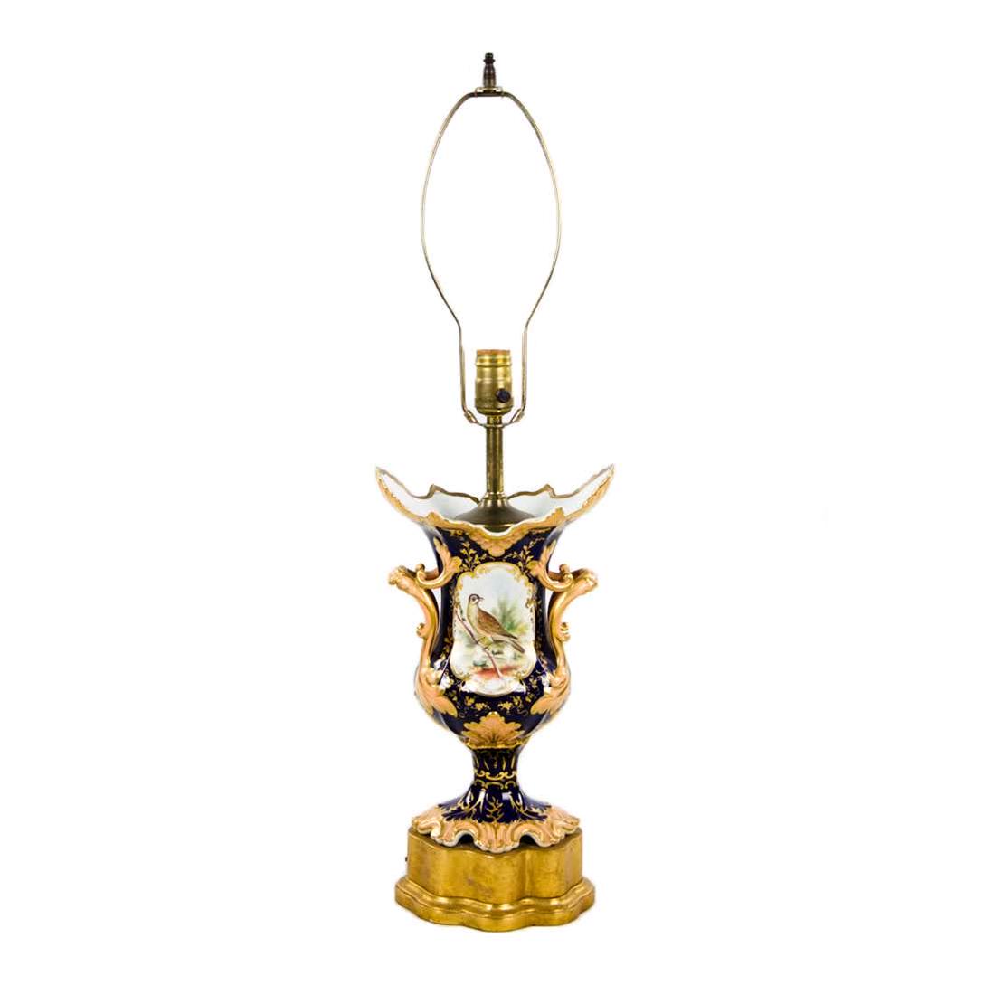 French Louis XVI Cobalt Blue Lamp: A blue cobalt vase lamp possible antique having bird and floral motif with scalloped top edge and gilt wooden base. modern brown cloth cord harp and finial. Dimensions: 28.5"H x 6.5"W x 5.5"D Flat Rat