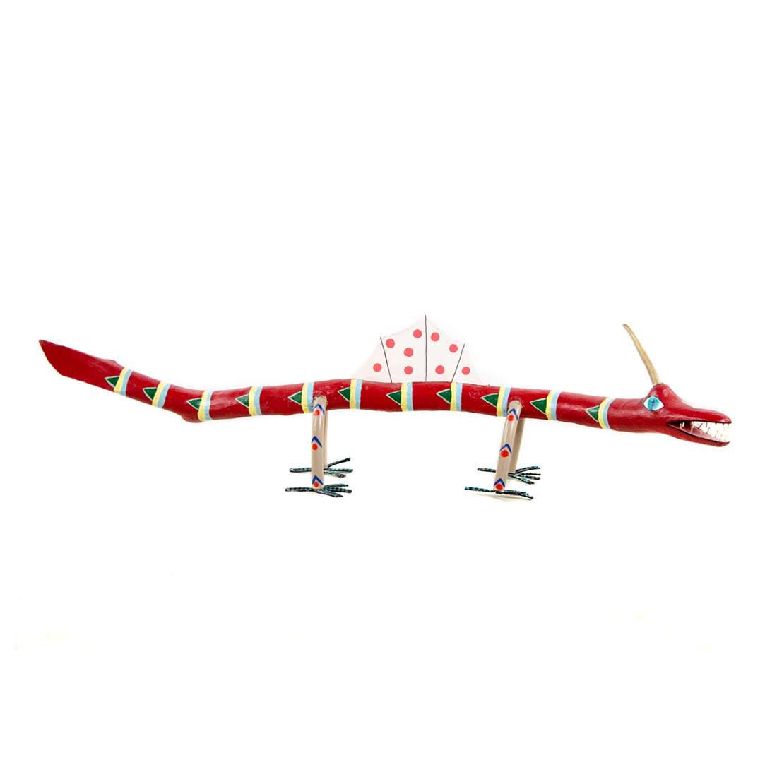 Folk Art Hand-Painted Wooden Dragon Sculpture: A folk art wooden dragon sculpture. This piece features an elongated form with a horn on its head and a dorsal frill on its back. It is decorated with hand-painted geometric designs throughout in a pa