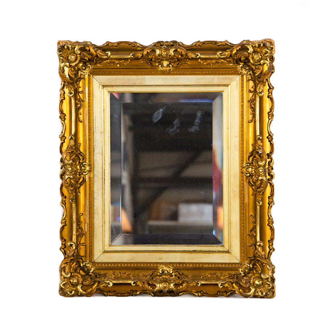 Antique Carved Giltwood Mirror: An antique mirror. This piece features a giltwood frame with floral and foliate carvings throughout. It is unmarked and equipped with a wire on the verso for hanging. Condition: Wear consistent with a