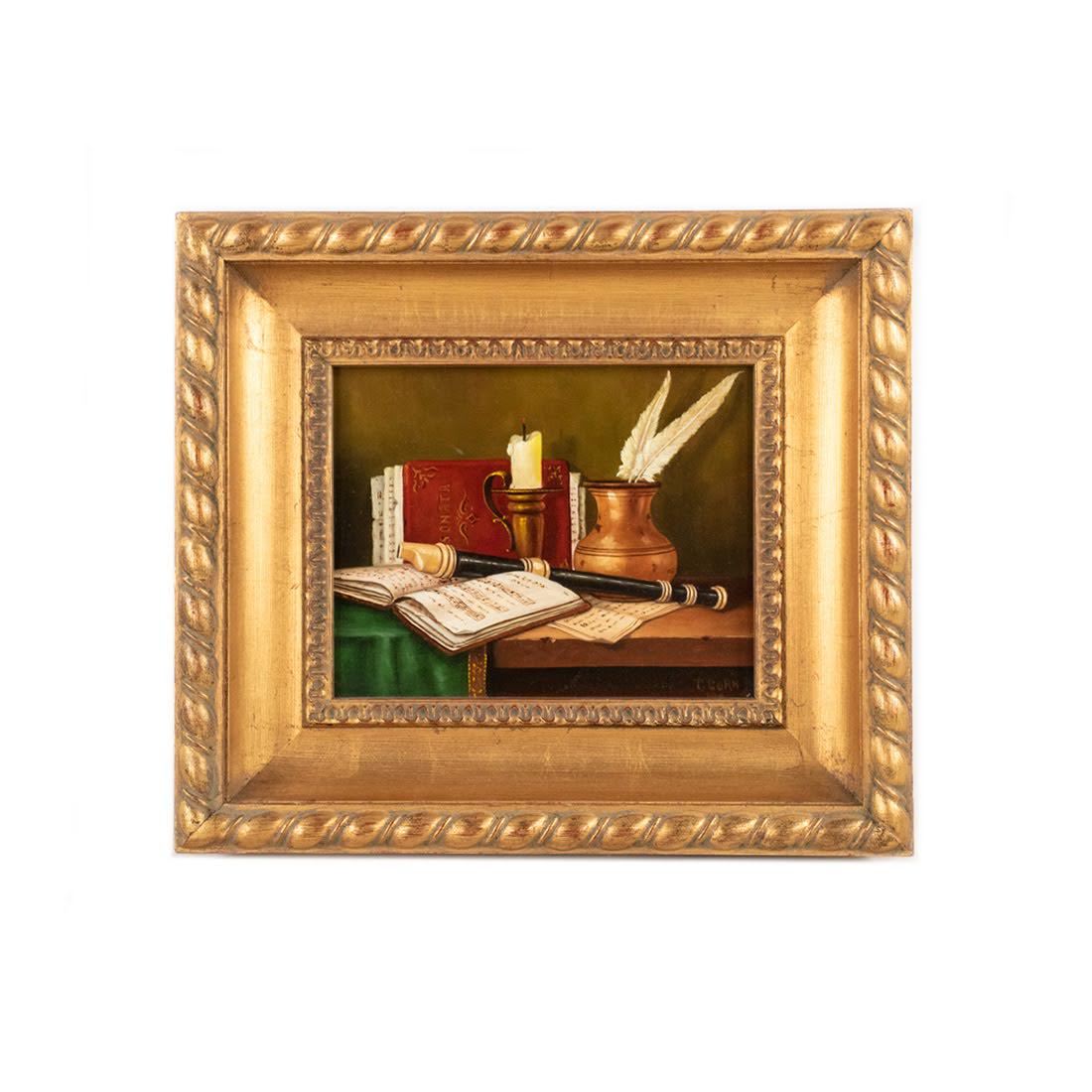 T. Corn Wood Print Still Life: A board printed still life of sheet music and instruments on a desk signed T. Corn. It is presented in a carved gilt frame.