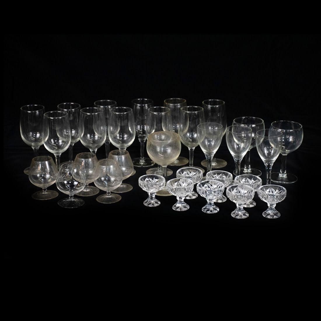 Group of 30 Assorted Wine Glasses and Coupes: A group of 30 assorted glassware pieces including 11 wine glasses, 8 miniature cut glass goblets, 5 goblets, 2 round wine glasses, 3 smaller wine glasses, 1 amber tone wine glass. There are no visible