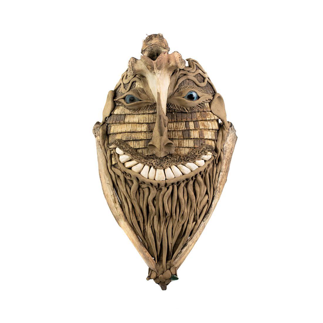 South American Brazil Ceremonial Tortoise Shell Mask: A South American Brazilian ceremonial mask mixed media consisting of animal bone, clay, glass eyes, animal teeth, tortoise shell, and stones depicting a grinning smiling face with long beard, high cre