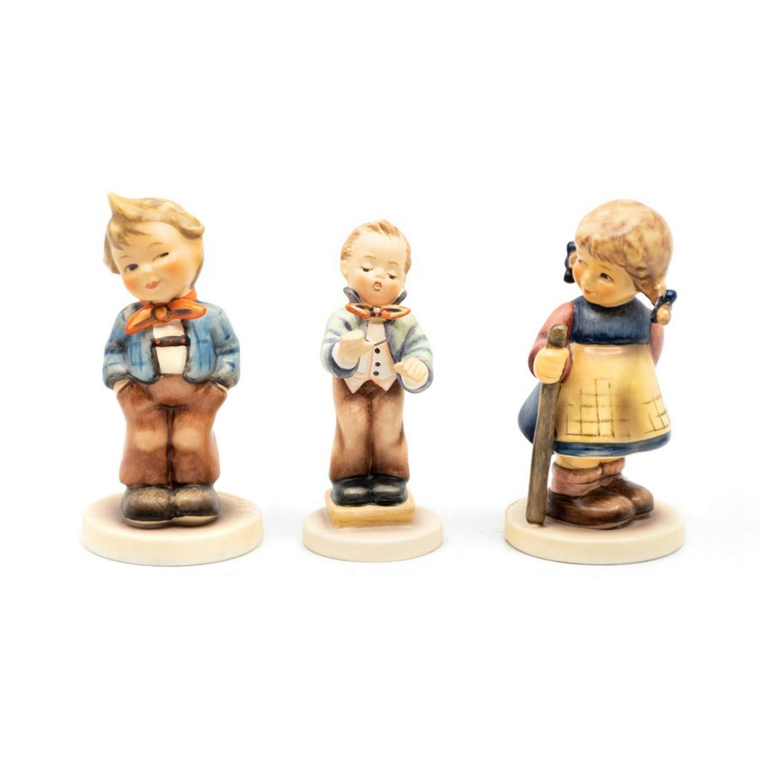 Group of 3 Goebel Hummels including Scamp 553: Goebel Hummel #553 Scamp TMK 7 features a winking boy with his hands in his pockets, #129/4/0 Band Leader TMK 6 features a boy in tie and tails conducting a band, and #768 Pixie TMK 7 features a winki