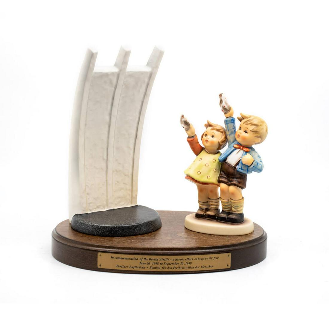 Goebel Hummel Berlin Airlift Commemorative Set of 3: Goebel Hummel Berlin Airlift Commemorative Set features three pieces, a wooden base, a figure of two children waving, and a representation of the Berlin Wall.