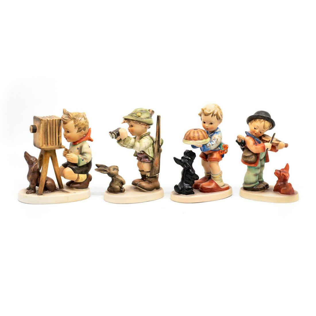 Group of 4 Goebel Hummels including Puppy Love 1: Goebel Hummel #178 The Photographer TMK 2 features a boy working a camera while a dog sits between the tripod legs, #307 Good Hunting TMK 4 features a boy with a rifle slung on his arm looking out of