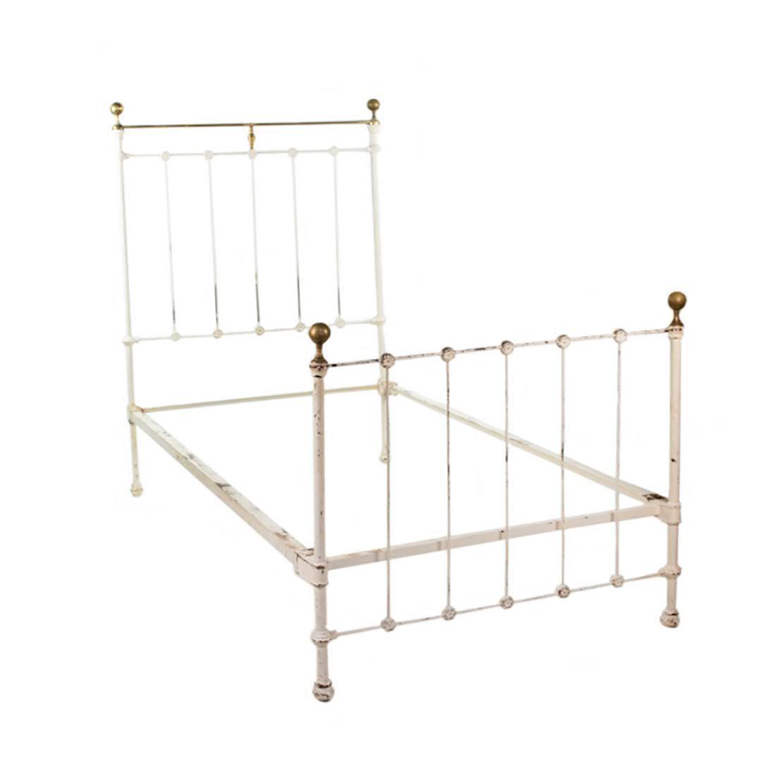White Wrought Iron and Brass Banister Single Bed: A turn of the century single white painted wrought iron bed having banister rail headboard and footboard with original rails and frame and brass bed knobs and upper railing.