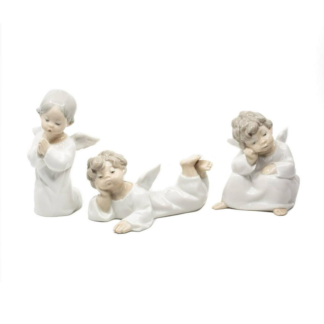 Set of 3 Lladro Porcelain Angels: A set of three Lladro porcelain angels including a thinking angel, a reclined angle, and a praying angel. All marked on the underside.