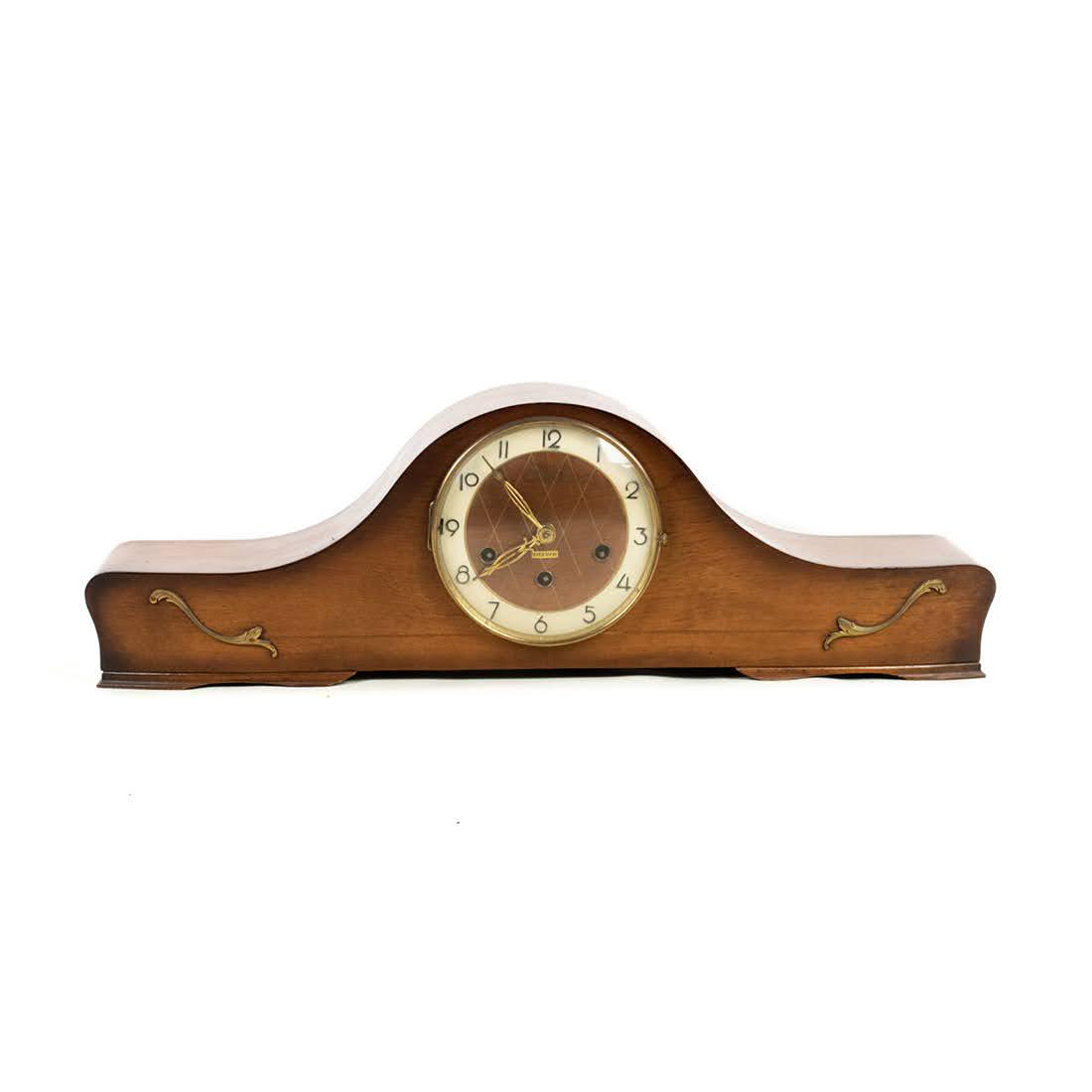 German Rolls Westminster Super Ancre Mantel Clock: A 20th century German Rolls Westminster Super Ancre mantel clock having shaped mahogany case with gilt metal accents, encasing a white metal painted face with Arabic numerals and gold tone hands. Mark