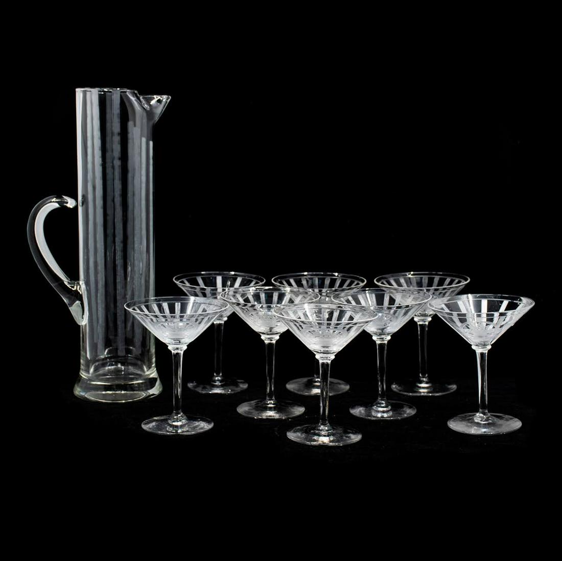 Set of 9 Etched Martini Glasses and Tall Pitcher: Set of 9 glass martini glasses having etched vertical lines with a small floral basket central motif and a tall etched glass pitcher having formed spout. Unmarked.