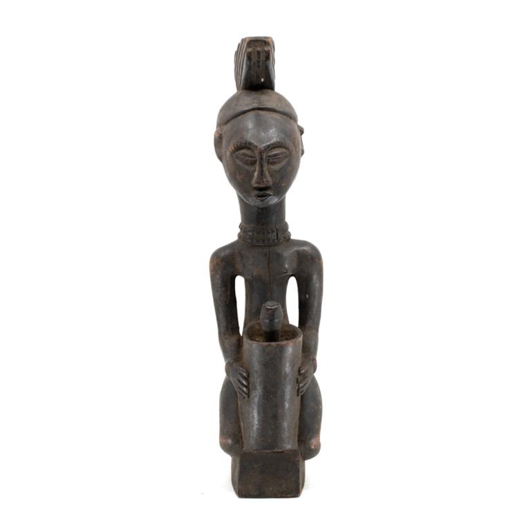 African Nigeria Yoruba Carved Female Figure: African Nigeria Yoruba Carved Female Figure, carved wood depicting a female figure having pronounced forehead central crest headdress, kneeling with mortar and pestle between hands on a small plinth.