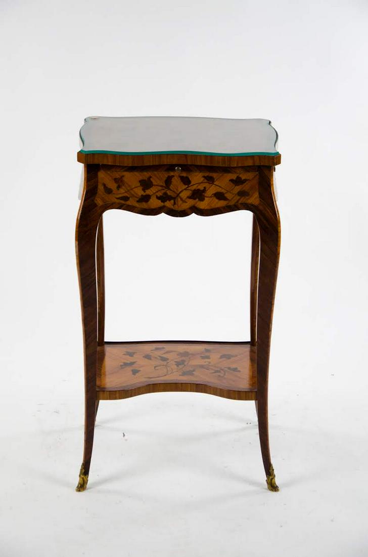 18th Century French Transitional Marquetry Side Table: An 18th century French Transitional marquetry table having glass cut top and inlaid marquetry with book matching designs. Features a small writing slide that pulls out one side and a drawer on the oth