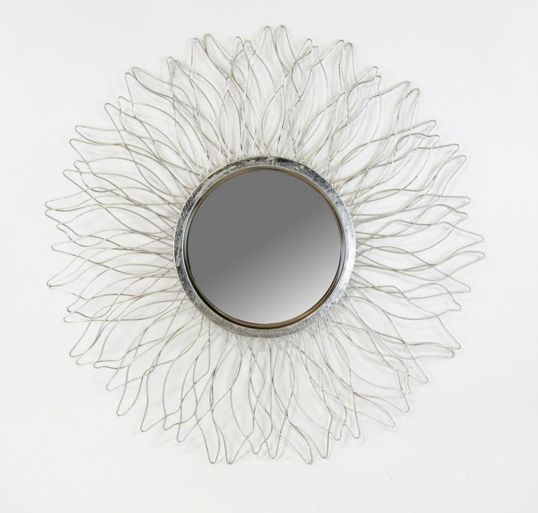 Contemporary Sunburst Wire Form Wall Mirror: A Contemporary sunburst wire form wall mirror having bent and twisted sun form with round mirrored glass in the center and a silver metal border. Hook on verso for hanging.