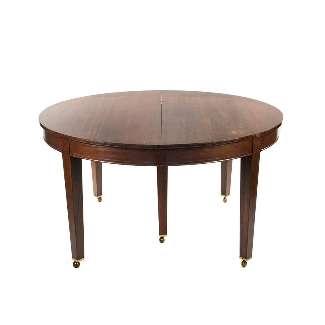 Federal Style Mahogany Extendable Dining Table: A vintage Federal style mahogany extending dining table. This piece features thin line inlay along the edges. It is raised atop six tapered rectangular legs with the two center legs being joined with 