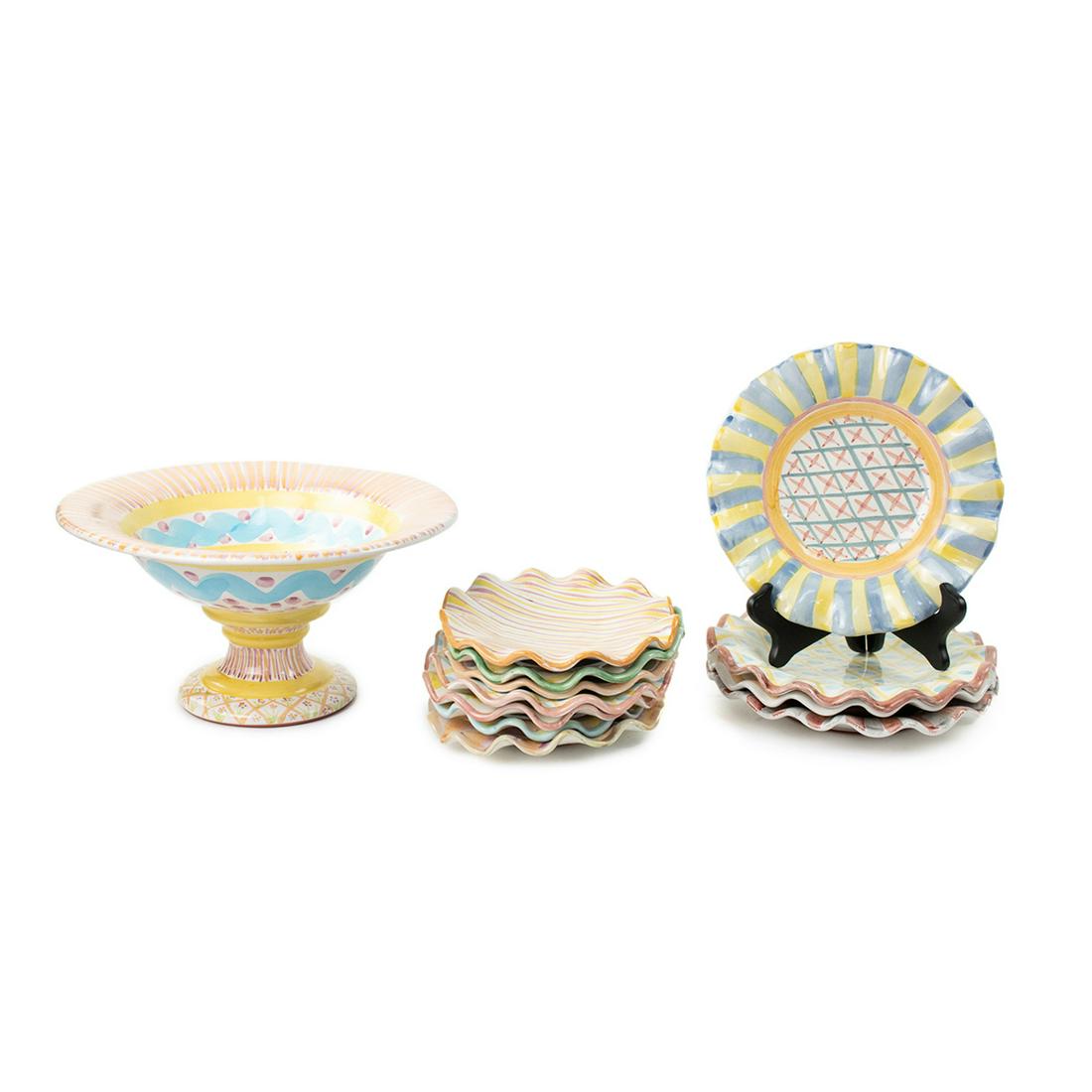 Grouping of MacKenzie-Childs Pottery Pieces: A grouping of vintage hand-painted terracotta pottery pieces by MacKenzie-Childs. This lot includes four salad plates, seven dessert plates, and compote. Each piece features a whimsical multi-colored 