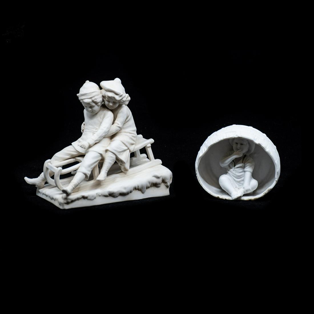19th C. Parian Bisque Sculptures: A grouping of two 19th century antique parian bisque porcelain sculptures, including a sculpture of a pair of children sledding and a sculpture of a seated child in a barrel. The sculpture of the chil