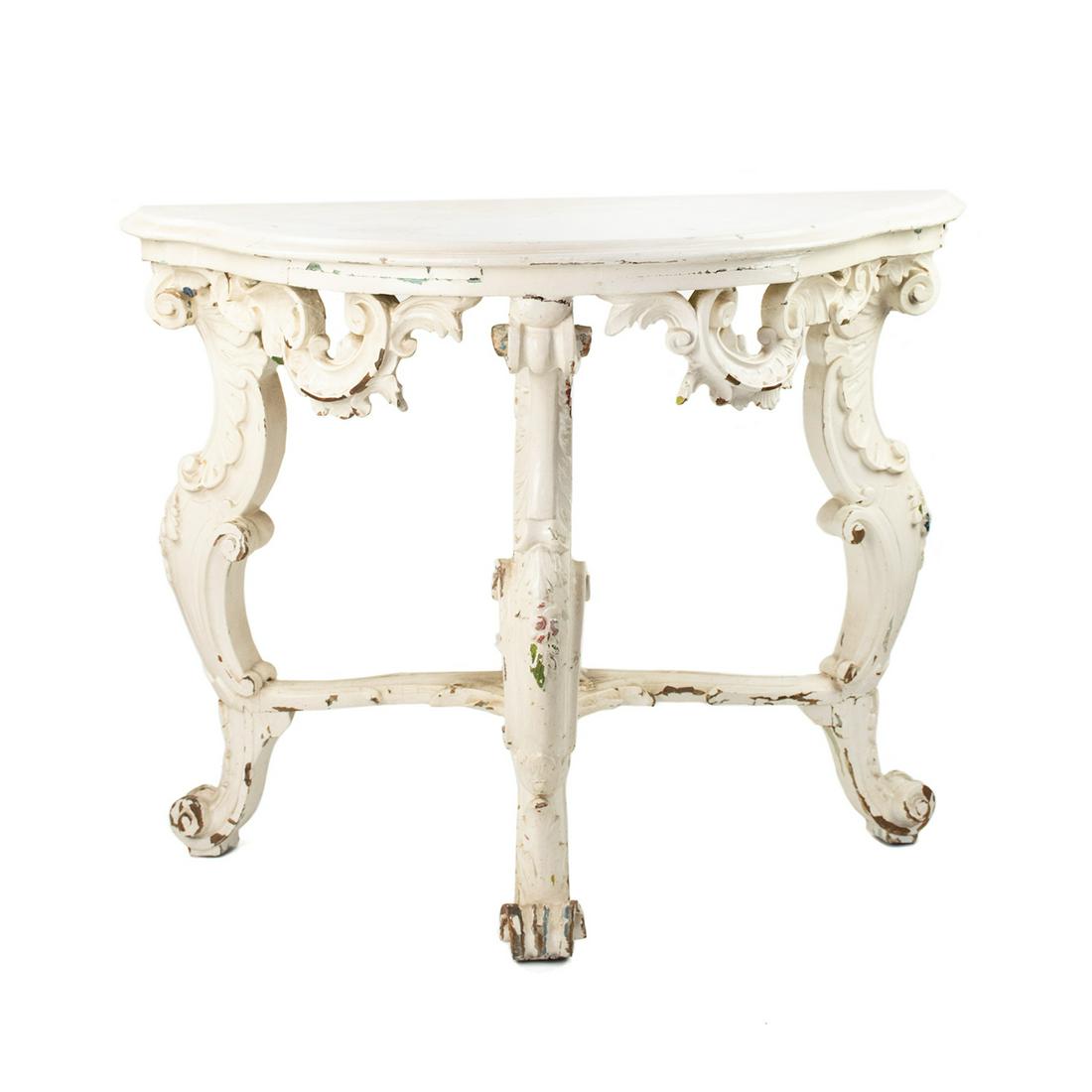 Antique Baroque Demilune Console Table: An antique Baroque style white painted wooden demilune console table featuring a curved half-moon table top, an ornately carved foliate motif apron, and carved cabriole legs with scroll feet supported