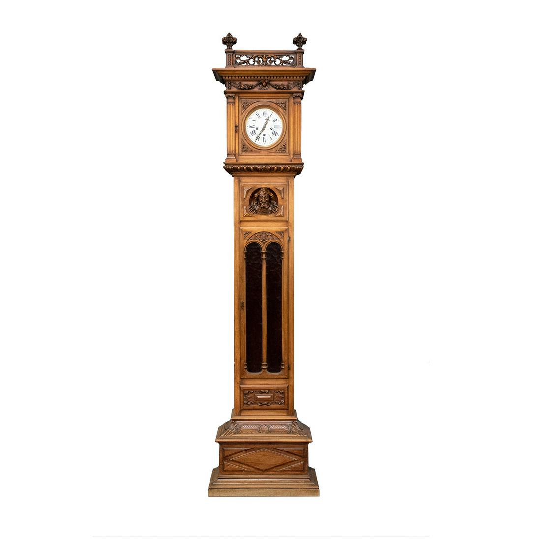 Gothic Revival Style Grandfather Clock: A vintage Italian Gothic revival style Grandfather clock. The upper portion of this piece features a round white clock face flanked by carved wooden column motifs and topped with an ornately carved cr