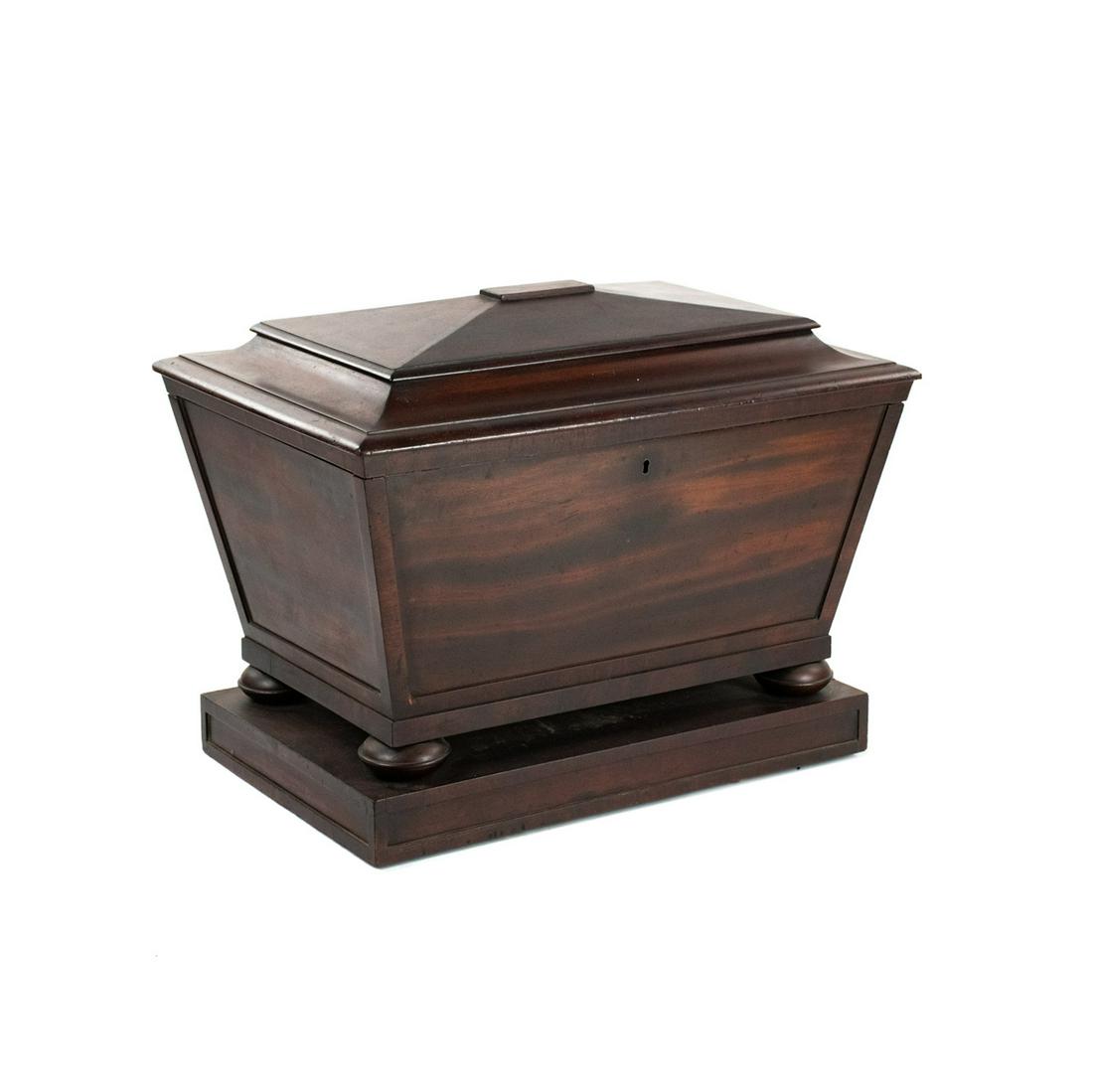 Regency Period Flared Side Sarcophagus Form Cellaret: A Regency period flared side sarcophagus form mahogany cellarette wine cooler chest having tapered body with lead liner with compartments dividers for storing wine resting atop a rectangular base. It 