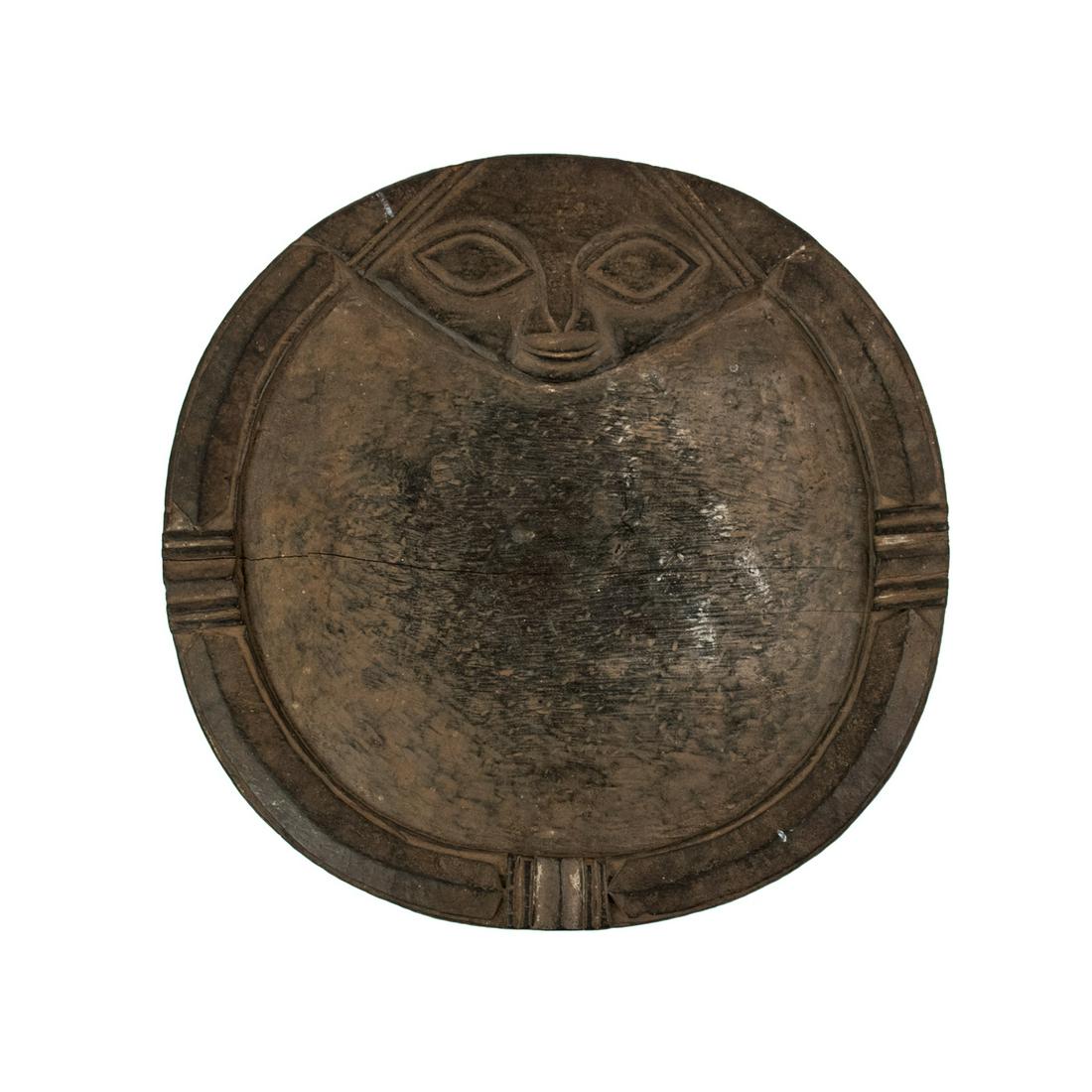 African Nigeria Yoruba Divination Plate: An African Nigeria Yoruba tribe divination plate carved from a single piece of wood having carved incised border with humanistic face at top showing wear at center from use.