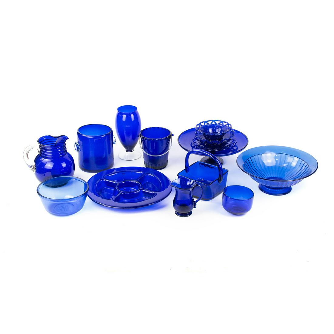 Grouping of Cobalt Blue Glass Dish and Serveware: A grouping of cobalt blue glass dishware and serveware including two ice glass buckets, one with metal handle, a cobalt blue vase with clear base, one large pitcher with clear handle, one small cobalt