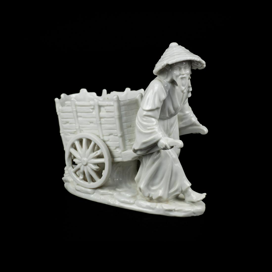 Rosenthal-Netter Blanc de Chine Man with Cart: A vintage Rosenthal-Netter blanc de chine figure depicting an older Chinese man wearing a traditional straw hat pulling an old wooden cart on oval base. Marked with sticker on underside.