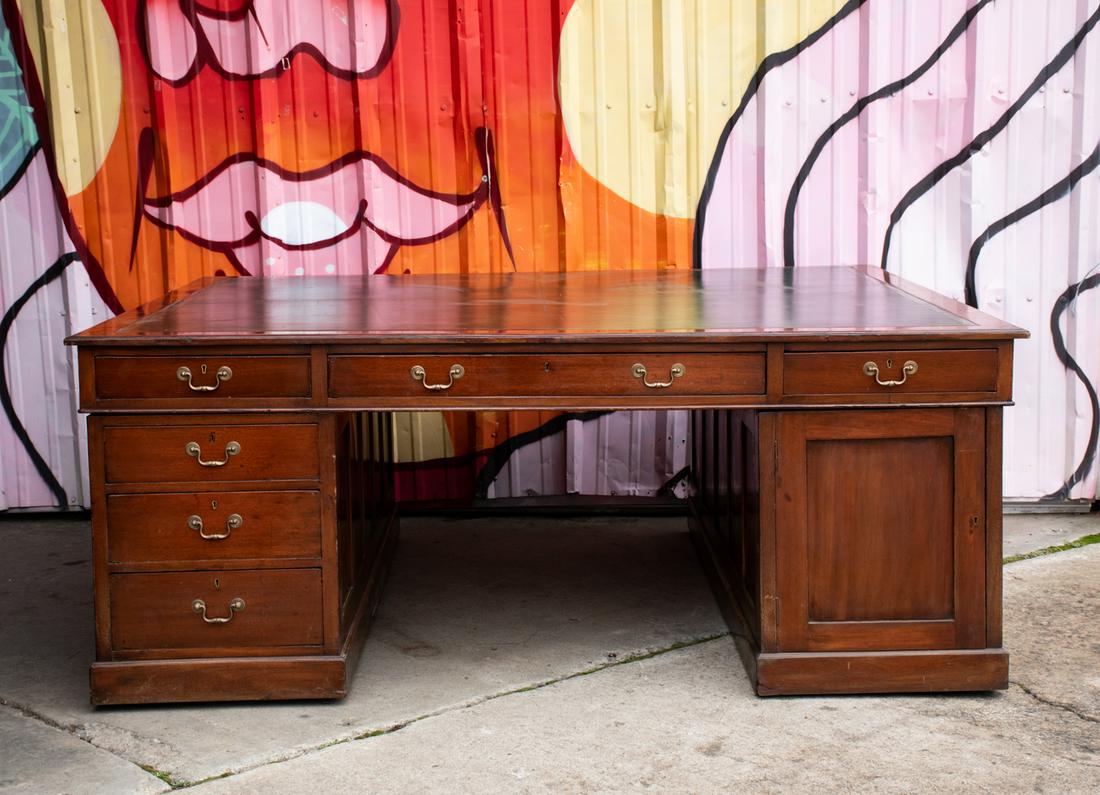 Colossal English Mahogany Green Leather Partners Desk: A colossal antique English mahogany partners desk having green leather and gilt embossed top with six drawers, all with brass pulls and key holes, and one door on the right side. Very large. Unmarked.