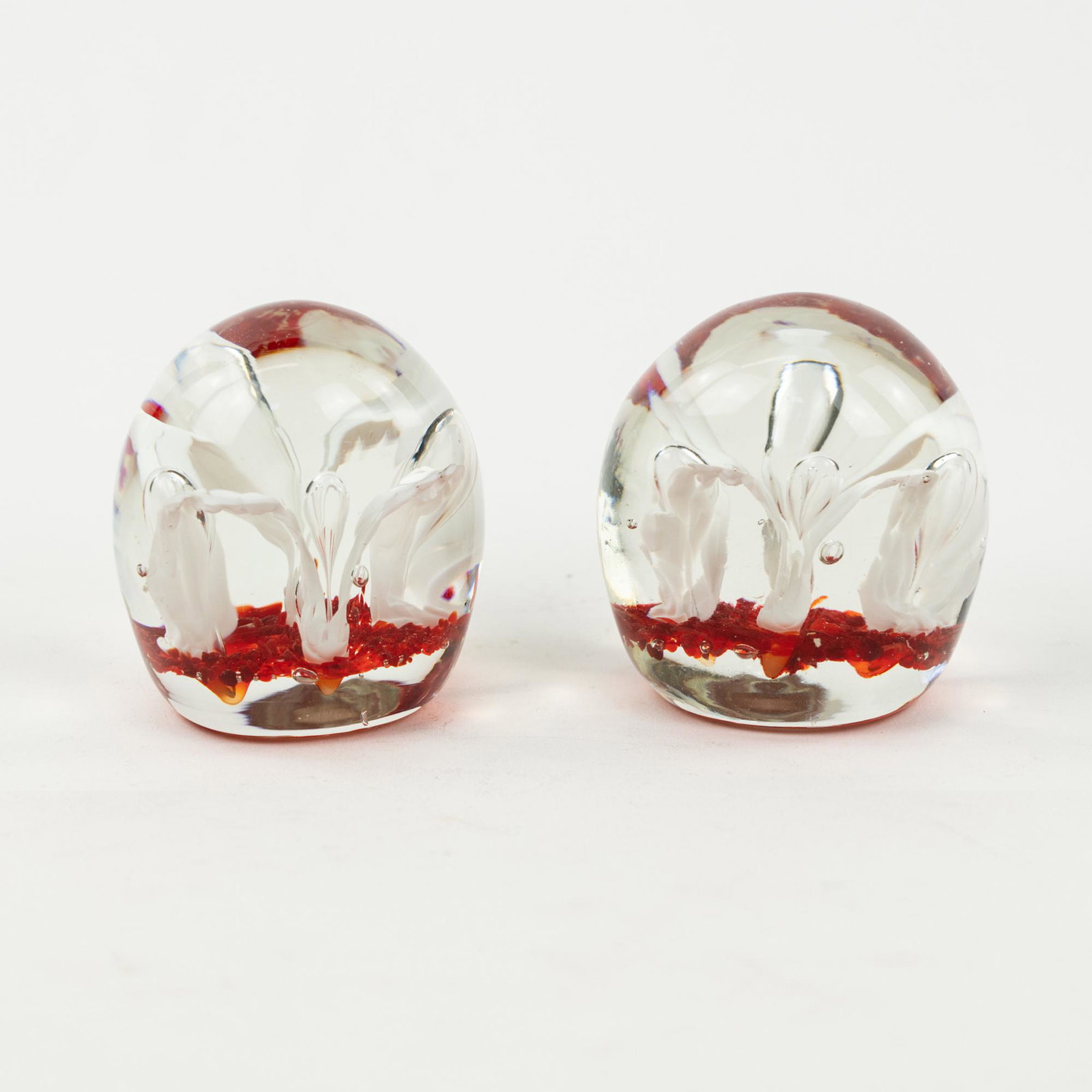 (2) Pair of Red Floral Glass Bookends / Paperweights: A pair of Murano style red flower blown glass ball paperweights possibly bookends having a round shape with one flat side on each. Unmarked