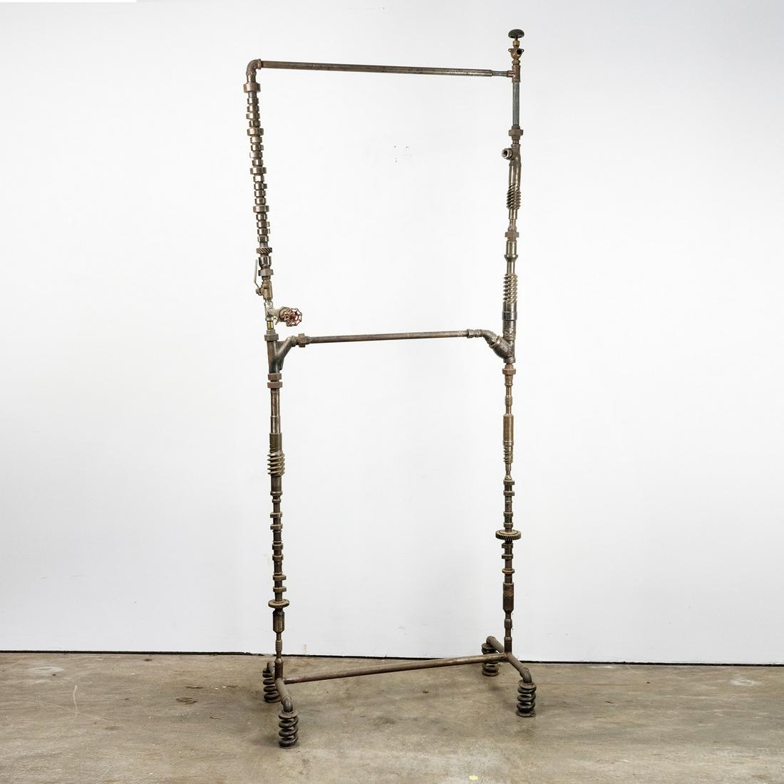Pipes & Fittings Clothing Rack Sculpture: An industrial sculpture in the form of a 2-tiered clothing rack composed of assembled found plumbing pipes, fittings, and other found objects including valves, gears, a car camshaft, and other materia