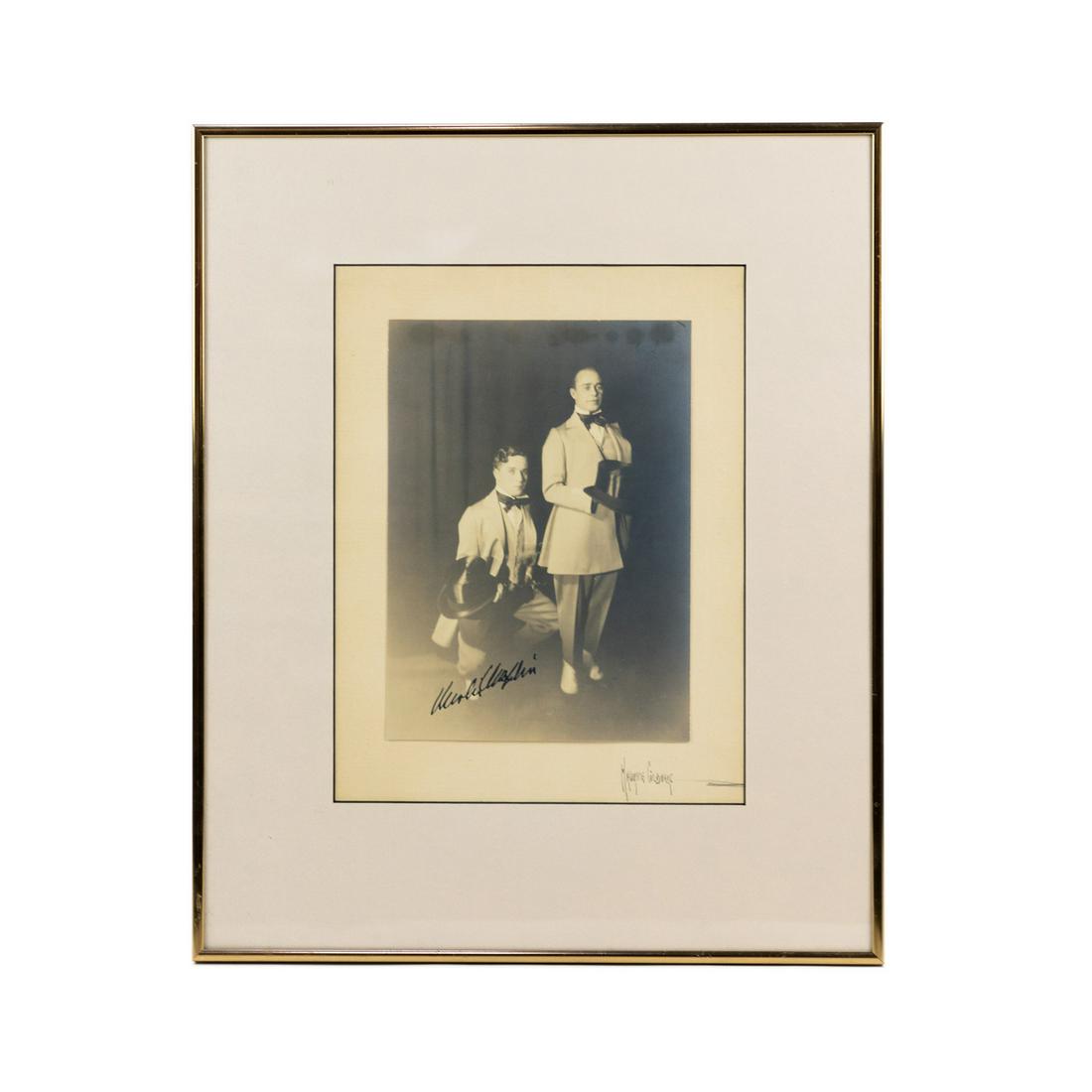 Charlie Chaplin Autographed Photo by Maurice Goldberg: A Charlie Chaplin (English, 1889-1977) autograph in black felt pen signed on an early 20th century black and white gelatin portrait photograph of the comedian and film producer on one knee and holding