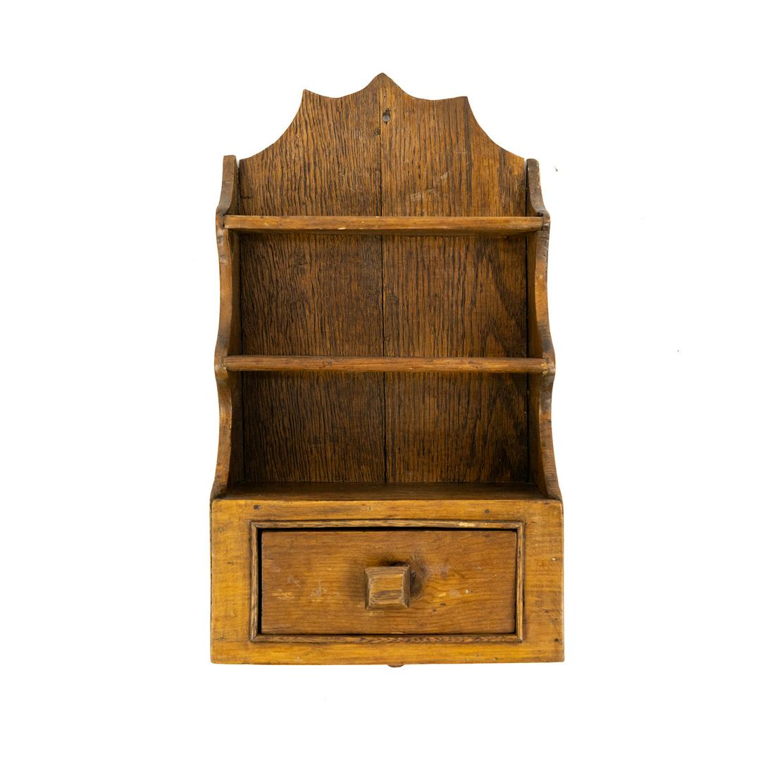 Miniature Hanging Cupboard: A miniature hand-made hanging cupboard having 3-tiered shelving and a single drawer with single square knob and carved scalloped edges. Hole drilled in the top center for wall mounting.