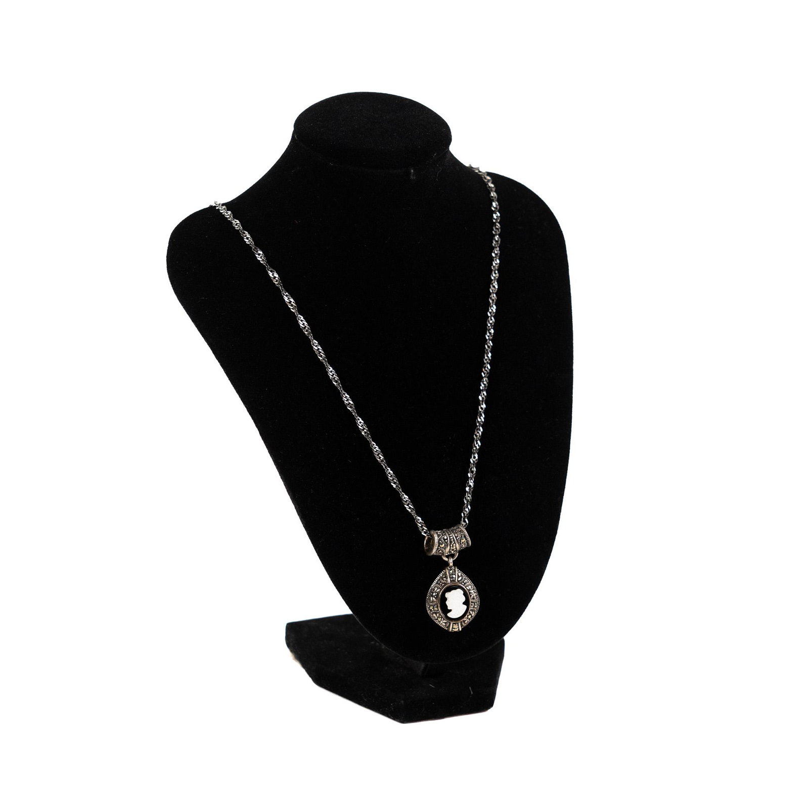 Sterling Silver & Marcasite Cameo Pendant Necklace: A sterling silver and black marcasite white cameo dangle pendant necklace on braided chain with clip clasp measuring 22 and 1/4 inches and weighing .64ozt. Marked 'Made in Italy' on inside of clasp.