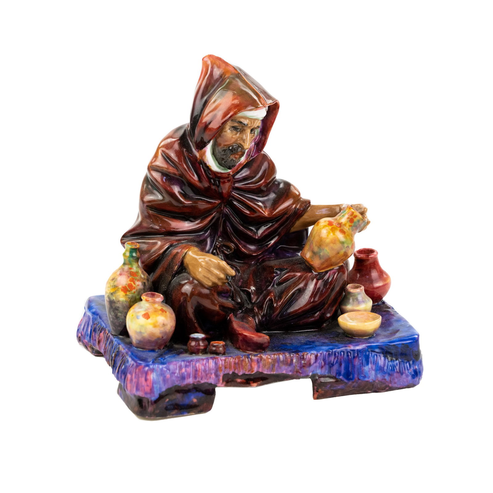 Royal Doulton 'The Potter' Bone China Figurine: A Royal Doulton "The Potter" bone china figurine depicting a man sitting cross-legged on a carpet and presenting his wares. Marked on undersided HN 1493.