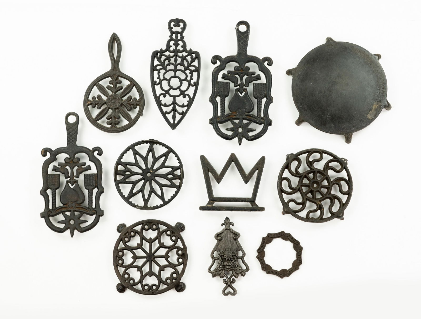 Grouping of Iron and Brass Trivets: A large grouping of various types of trivets cast from iron including teapot and iron trivets.