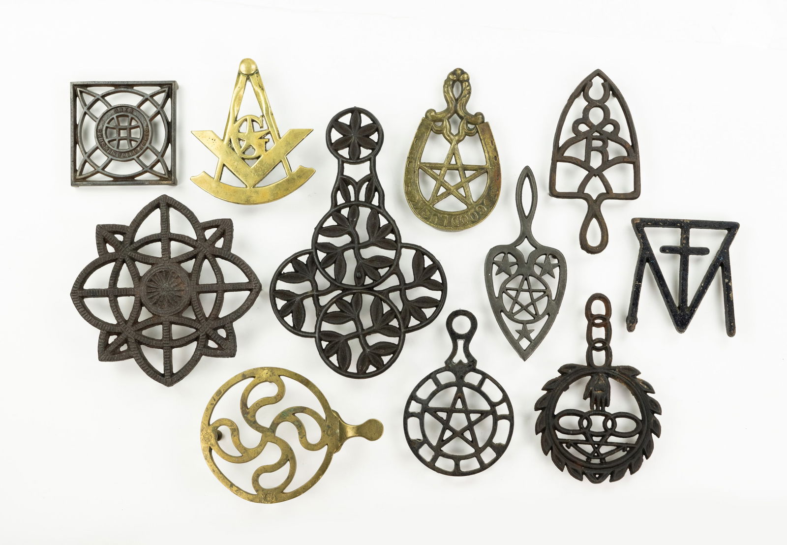 Grouping of Iron and Brass Trivets: A large grouping of various types of trivets cast from iron and brass including teapot and iron trivets.