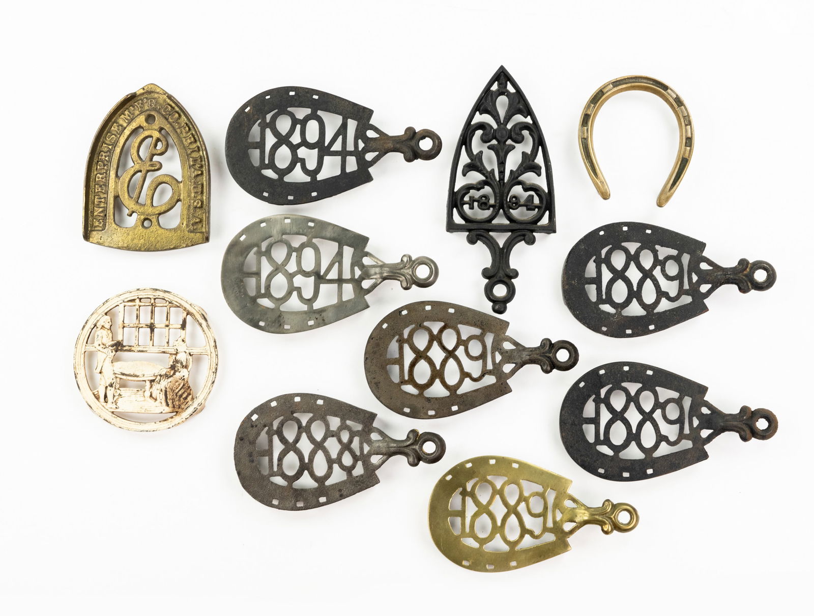 Grouping of Iron and Brass Trivets: A large grouping of various types of trivets cast from iron and brass including teapot and iron trivets.