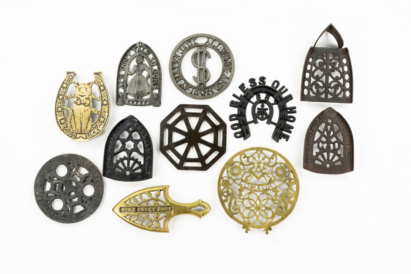 Grouping of Iron and Brass Trivets: A large grouping of various types of trivets cast from iron and brass including teapot and iron trivets.