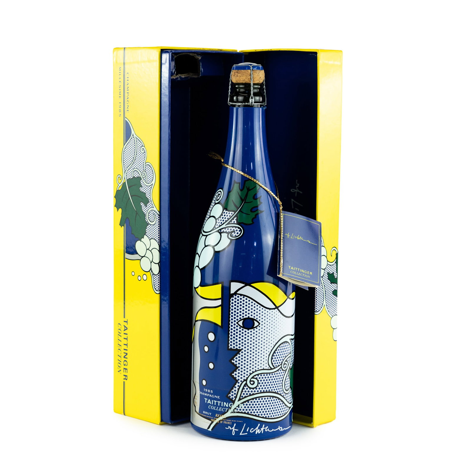 1985 Taittinger Limited Ed. Lichtenstein Champagne: A sealed 1985 Brut champagne bottle featuring screen printed Roy Lichtenstein artwork on the label along with his printed signature near the bottom; two bottles having a printed information tag tied t