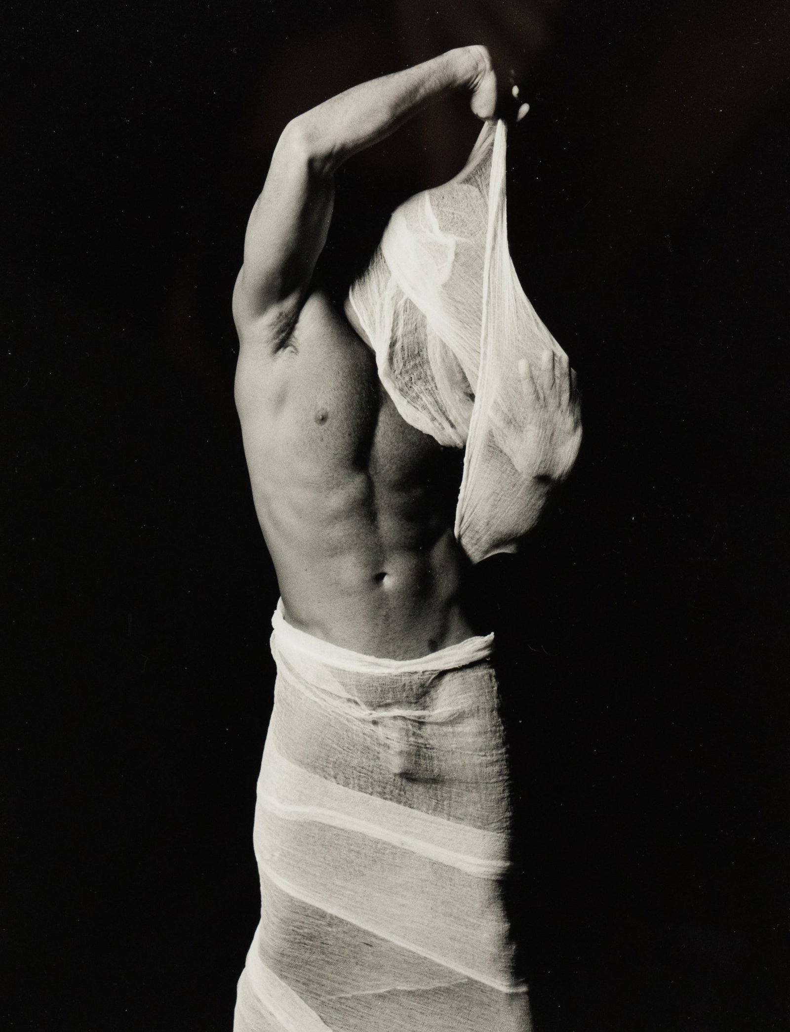 Tim Wilkerson 'Emerging' Male Nude Photograph: A Tim Wilkerson (American, 1957-2018) black and white photograph titled 'Emerging' depicting a nude man removing a cloth from his arms and head, Pencil signed and dated '1999' lower right and titled l