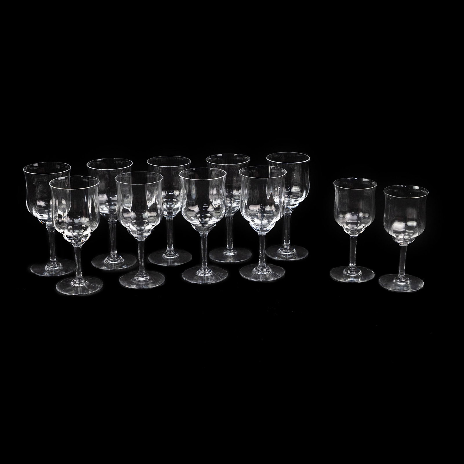 (11) Baccarat Crystal Capris Wine Glass Set: A set of eleven (11) Baccarat crystal capris wine glasses, nine tall and two short, having beveled bodies with flared mouths. Marked 'Baccarat' on underside. Measurements are for taller glasses.