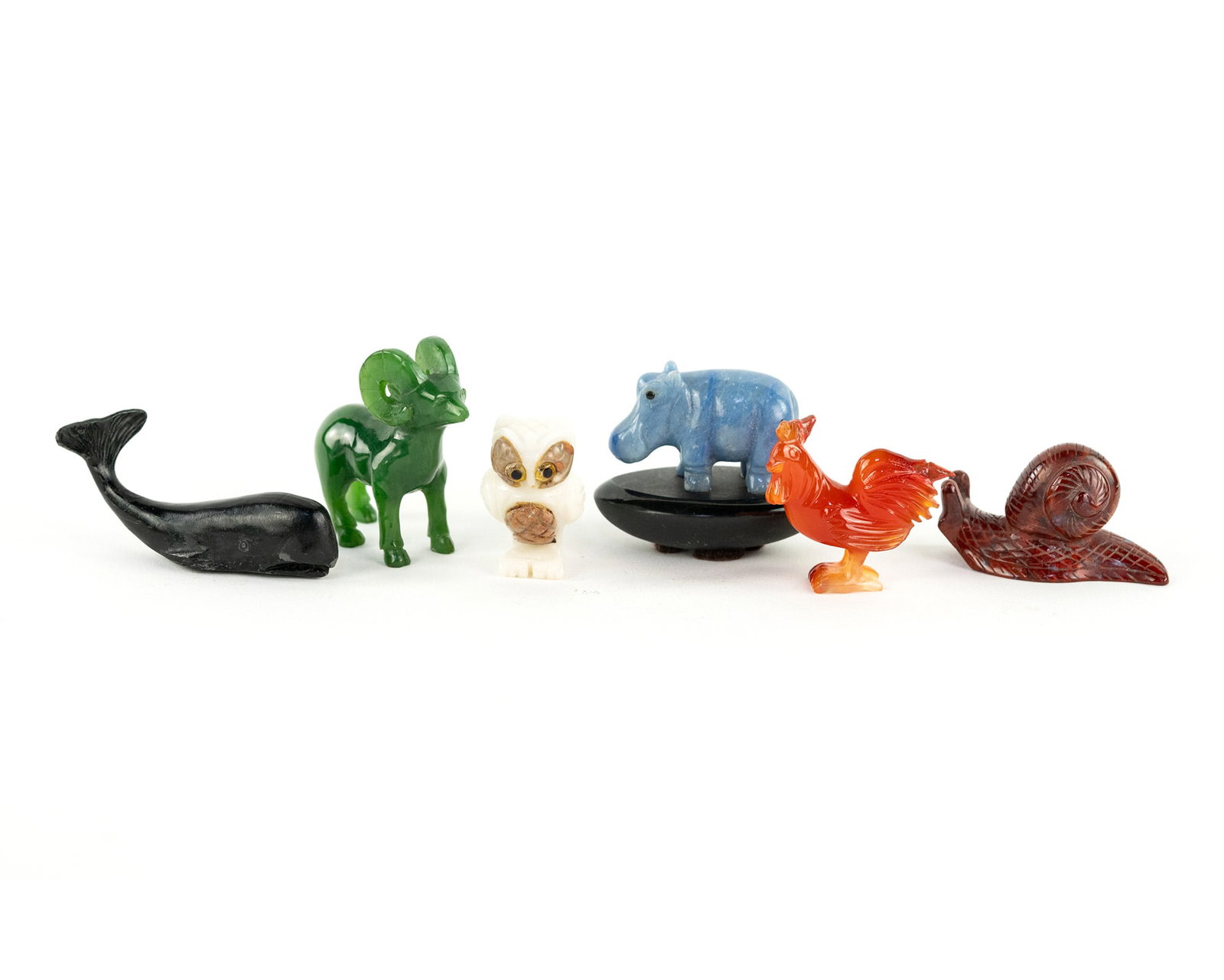 (6) Group of Assorted Animal Figurines inc Blue Quartz Hippo: A group of (6) assorted animal figurines including: a metal whale painted black, a green hardstone ram, a white and brown hardstone owl, a light blue hardstone hippo, a orange-red carnelian chicken, a