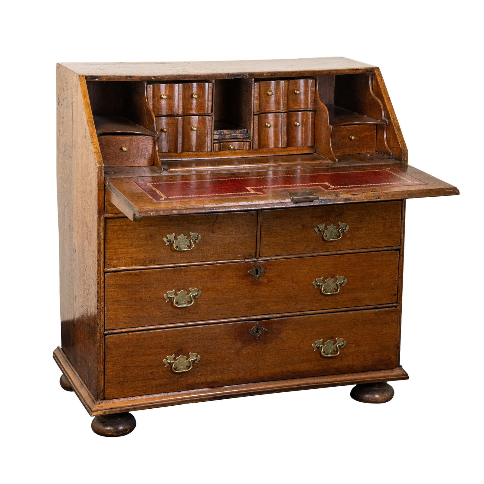 English Oak Leather Top Drop Front Secretaire Desk: A English oak leather top drop front secretaire desk having bun style feet, four larger lower drawers and ten smaller inner compartments in the top portion, and featuring all brass pulls. SHIPPING Atl