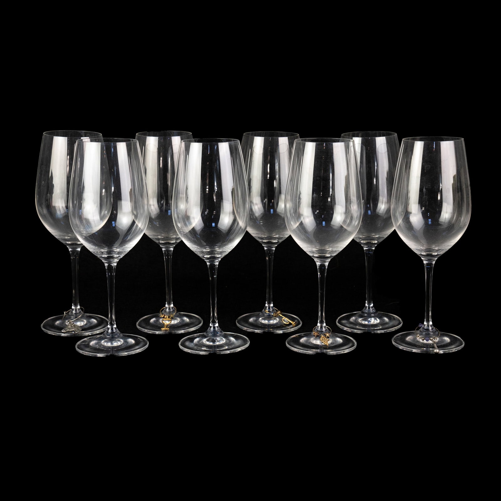 (8) Set of Riedel Crystal Wine Glasses: A set of (8) Riedel crystal wine glasses; five of the eight having a small metal charm depicting a different object. Each stamped on the base. SHIPPING Atlanta Auction Gallery will NOT ship this lot i