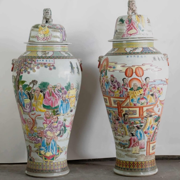 PAIR OF CHINESE FAMILLE ROSE TEMPLE JARS: Pair of Chinese famille rose temple jars in baluster form with domed covers and guardian lion finials; famille rose enamels with crowded figural scenes and auspicious motifs; applied mask and ring han