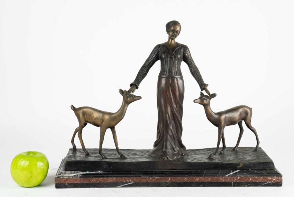 AFTER CHIPARUS, 'DEER LADY' BRONZE FIGURE: After Demetre Chiparus. Figure of a woman with her slender silhouette resting her hands on the heads of two graceful deer, mounted on striking base. Note: Each lot in this auction was stored in an act