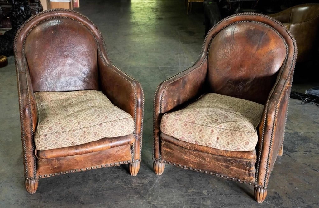 ENGLISH ANTIQUE LEATHER NAIL HEAD CLUB CHAIRS: English, early antique century. Arched back, nail head, leather, hay- & burlap-filled. Leather is heavily distressed. Used in the movie "hunger games". Note: Each lot in this auction was stored in an