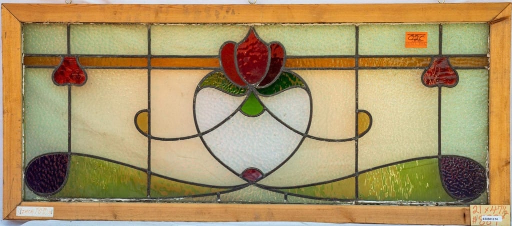 FRENCH ART NOUVEAU STAINED GLASS PANEL: French Art Nouveau stained glass panel with a red floral medallion surrounded by purple, green, and amber accents. Approximate dimensions: h. 21", w. 47.5" Disclaimer: This is an online court ordered