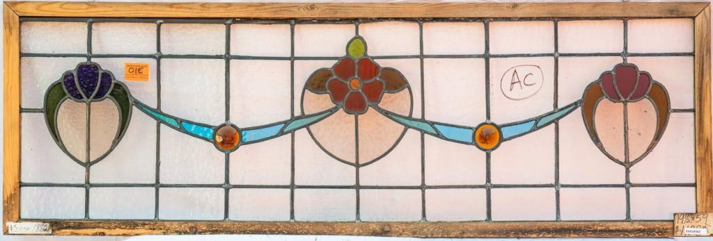 FRENCH ART NOUVEAU JEWELED STAINED GLASS PANEL: French Art Nouveau jeweled stained glass panel with floral and ribbon stained glass motifs, enhanced with jeweled accents. Approximate dimensions: h. 19.5", w. 59" Disclaimer: This is an online court