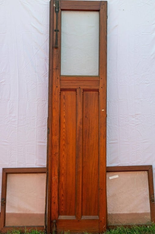 ANTIQUE HARD PINE FROSTED GLASS DOOR: Antique hard pine frosted glass door with two ventilation windows with frosted glass panels and a slide lock. Approximate dimensions: h. 98", w. 24"; h. 28", w. 22.5". Disclaimer: This is an online co